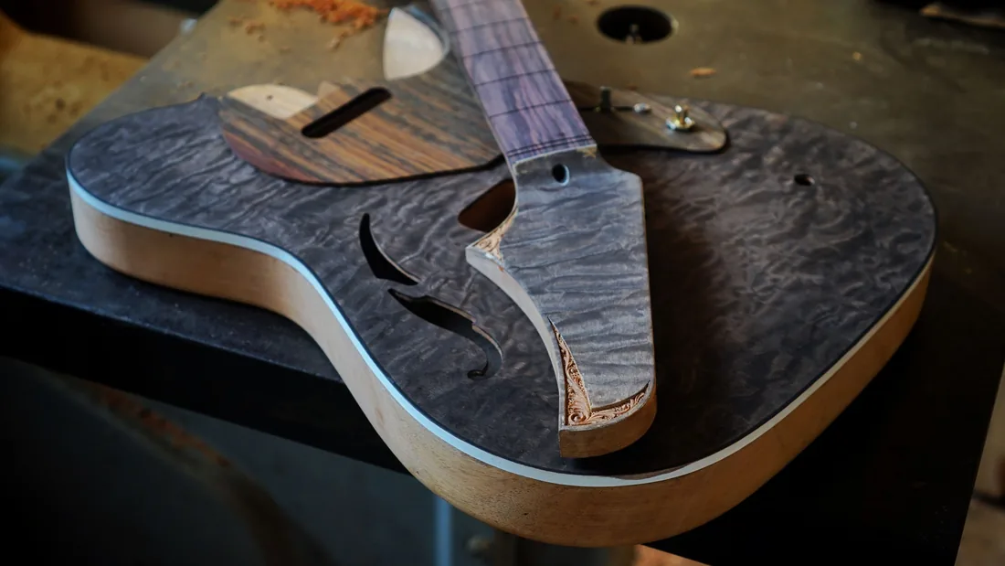 Caja de guitarra sin terminar sobre el banco del taller, con los aros, la tapa y el mástil todavía en bruto